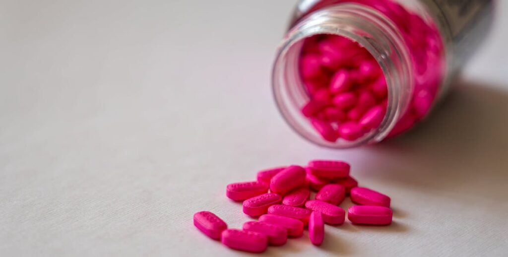 Pink pills spilling out of a jar.
