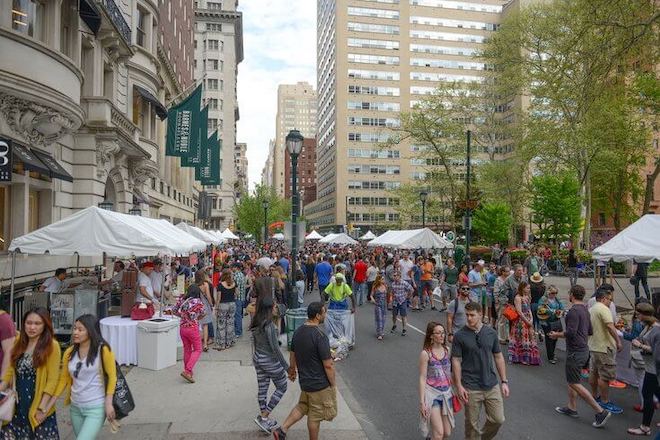 A group of people walk on Walnut Street, which is dotted with vendor stands — Rittenhouse Row Spring Festival