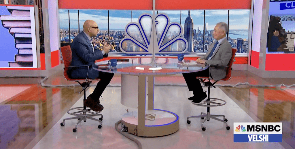 MSNBC host Ali Velshi and author, activist and actor George Takei sit on tall chairs at a tall table on the set of MSNBC to discuss Takei's book, "They Called Us Enemy."