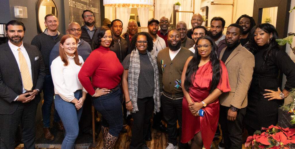 A group of about 20 mostly Black and Brown entrepreneurs and developers from Black Squirrel Collective stand in three rows, posing for the camera.