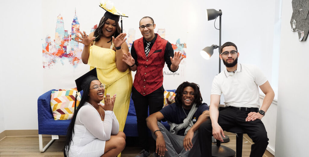 A group of five young adults, all dressed up, smile for the camera. They are graduates of Philadelphia's College Together.