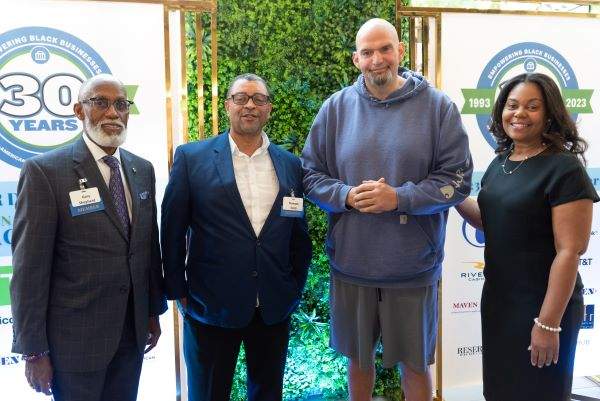 Two men and one woman standing with senator John Fetterman at a Philadelphia event
