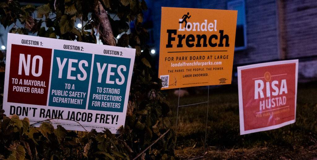 Three yard election signs — one about ballot measures, two for elected officials — stand in a snowy yard in Minneapolis in 2021.