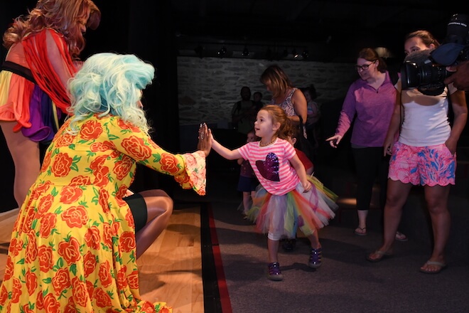Two drag performers in bright dresses greet children and their families at the Please Touch Museum as part of Drag Queen Storytime.