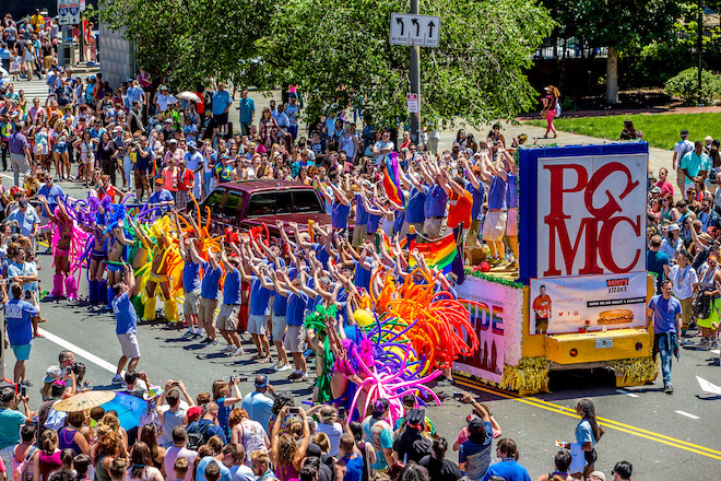 A float bearing the letters PGMC, displayed like Robert Indiana's LOVE sculpture travels along Market Street near Independence Mall in Philadelphia. This is the Philadelphia Gay Men's Chorus and the city's annual Pride Parade.