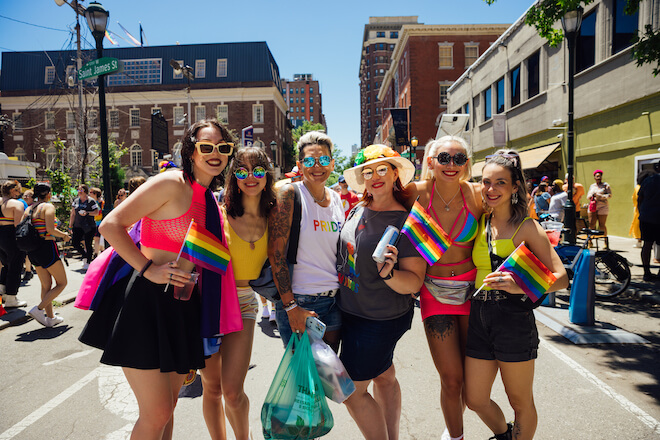 Five people stand on S. 13th Street in Philadelphia's Gayborhood on a sunny day, posing for the camera during Philadelphia's Pride festival.