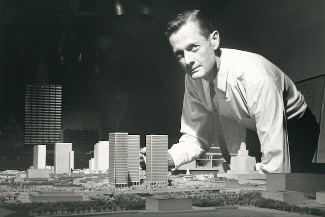 A black-and-white photo from 1960 shows a White man in a white shirt and dark tie leaning over a model of an apartment complex designed for the Society Hill section of Philadelphia.