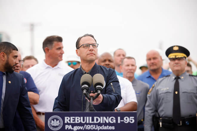 PA Governor Josh Shapiro stands behind a podium and in front of a crowd at the site of the I-95 collapse. Courtesy of Commonwealth Media.