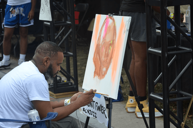 Philadelphia artist Demont Pinder paints on an easel at Cause Village, part of Made in America 2022.