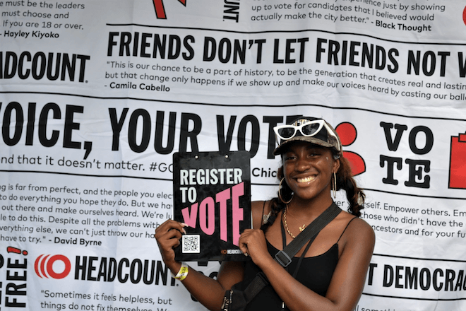 A volunteer from HeadCount, a national non-profit organization that works to register people to vote at music festivals, holds up a sign that reads, "REGISTER TO VOTE."