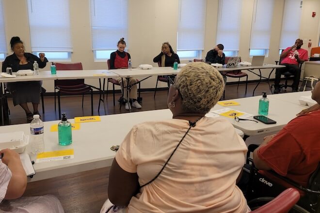 People sit around tables at a community center in West Philadelphia. They are training to become Documenters.