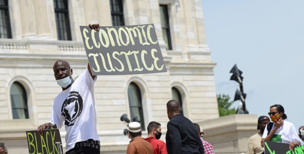 Man holding Economic Justice sign in a protest on Juneteenth.