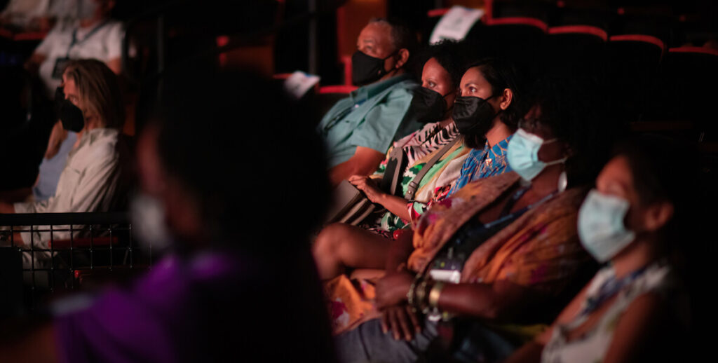 People wearing masks sit side by side in a cinema. They are audience members of BlackStar Film Festival.