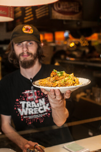 A bearded man with a cap holds a plate of Cajun food from Beck's Cafe in the Reading Terminal Market.