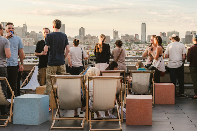 People gather on an outdoor rooftop bar at Philadelphia's Bok Building. Visible: the Philadelphia skyline.