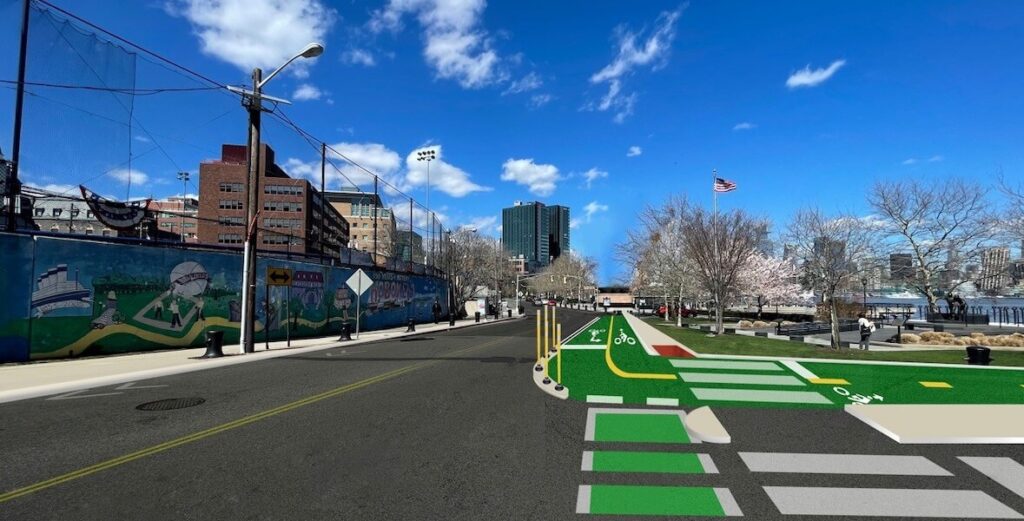 A streetscape of Hoboken, NJ shows a two-way street with a protected bike lane and sidewalk, part of the city's Vision Zero pedestrian and cyclist safety plan.