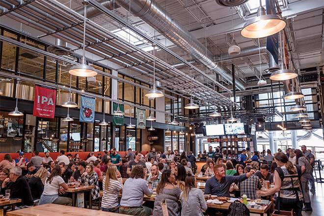 People sit at long tables inside a spacious, industrial-looking Yards Brewery in Philadelphia.