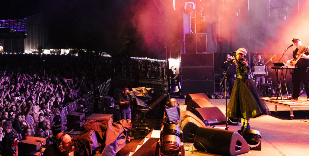 Lauryn Hill performing on a stage with a huge crowd in front of her.