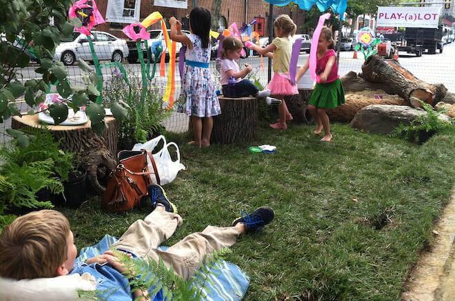 Children play and hang art on a sod parket on Park(ing) Day in Philadelphia.