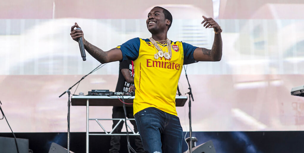 Meek Mill smiling, with arms outstretched, on stage at the Made in America festival in 2014.