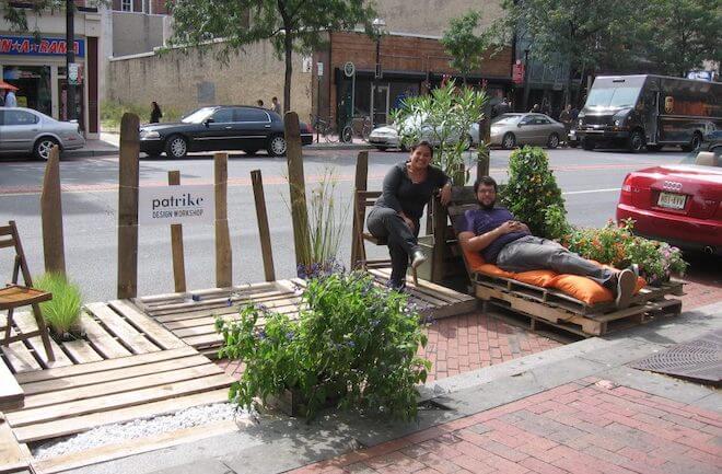 A woman squats near a man in a lounge chair in a parklet in Philadelphia on Park(ing) Day 2014.