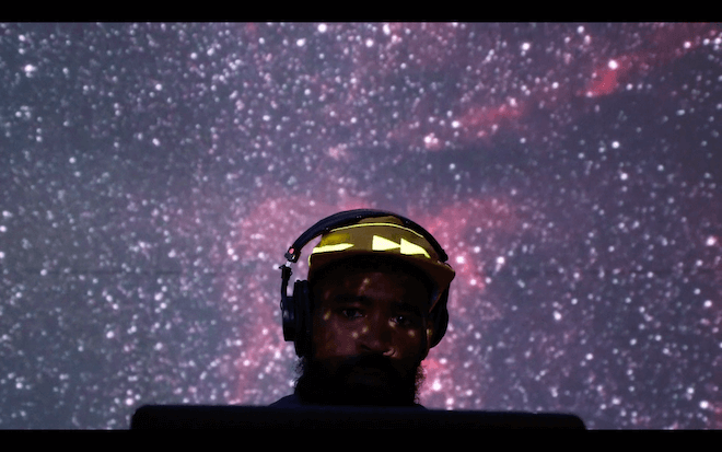 The top of the head of Rashid Zakat, a DJ, VJ and artist in Phialdelphia, appears in front of a galaxy-like backdrop.
