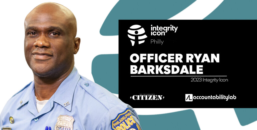 A portrait of Integrity Icon Ryan Barksdale, community relations officer in the 25th District and Black man in police officer's uniform, who is bald and smiling