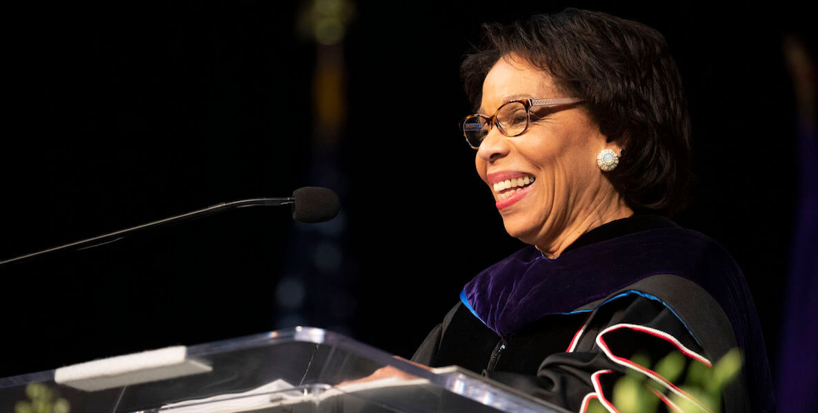 Temple University's JoAnne Epps speaks at a commencement, wearing a professor's robe and glasses.