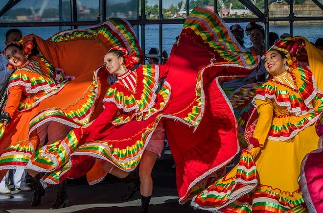 Women in bright ruffled dresses dance onstage at the Mexican Independence Day Festival at Penn's Landing.