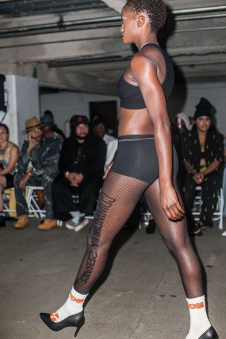 A model in couture athleisure walks the runway in a parking garage during Philadelphia Fashion Week.
