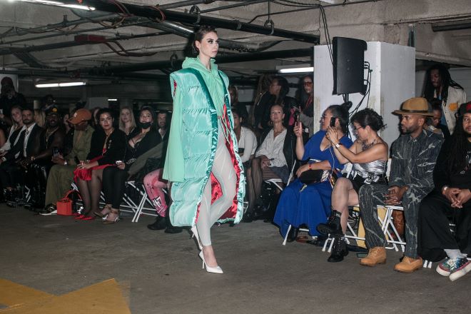 A model in a mint green t-length puffer jacket walks the runway in a parking garage during Philadelphia Fashion Week.