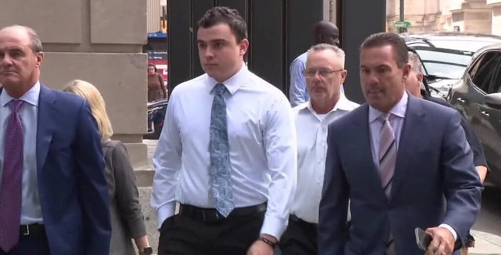 Former Philadelphia Police Officer Mark Dial (center) and attorneys, all White men in business attire, walk out of the municipal courthouse in Philadelphia.