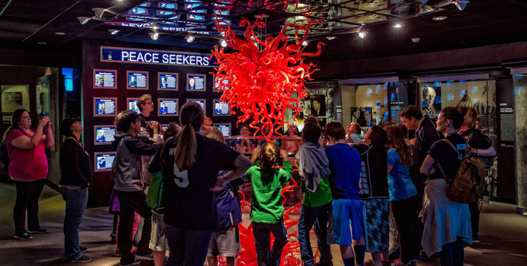 A crowd gathers around a red Dale Chihuly chandelier, make of glass tentacles, in the National Liberty Museum in Old City, Philadelphia.