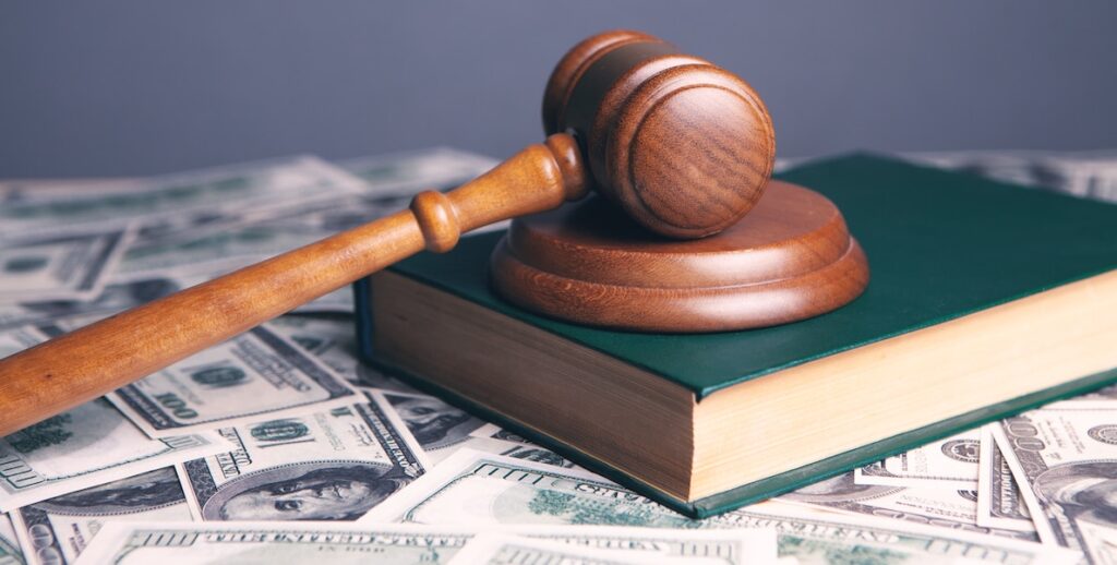 A judges' gavel atop a book and a bunch of money. This is a story about "magic seats" for judges.