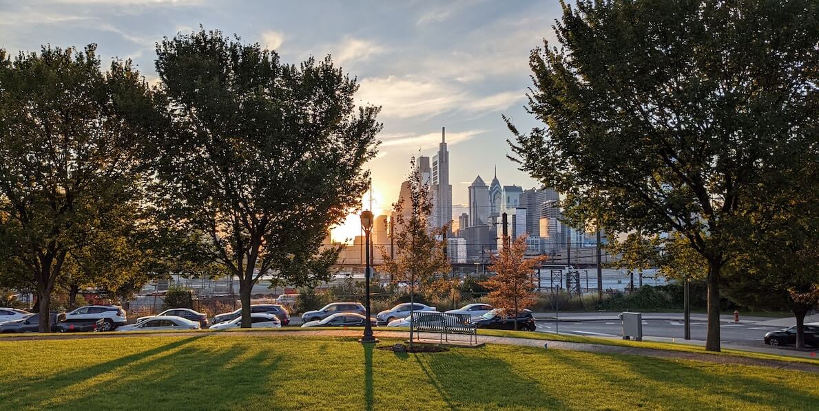 Trees and grass precede the river and in the distance, the skyline of Philadelphia's Center City section for a story on climate change.