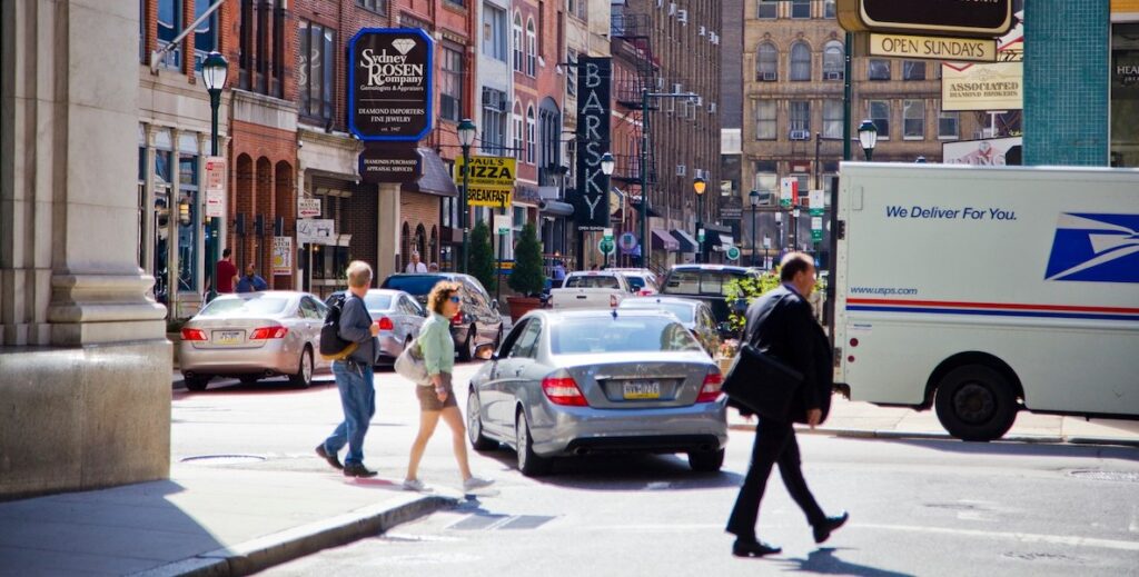 Pedestrians walk and cars drive in Jewelers' Row, a historic jewelry district in Center City Philadelphia.