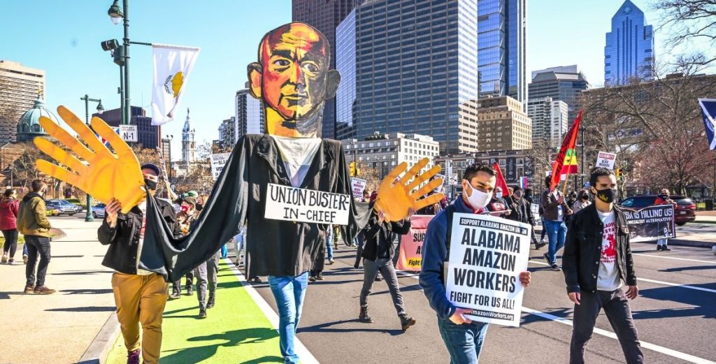 Pro-union demonstrators march down a city street with an effigy of Jeff Bezos in March 2021