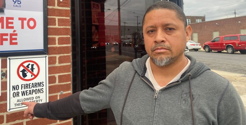 Pablo Solano said Philly cops have responded to the bar he manages quicker this year than in the past. He’s standing next to one of the signs posted on the bar’s exterior prohibiting firearms.