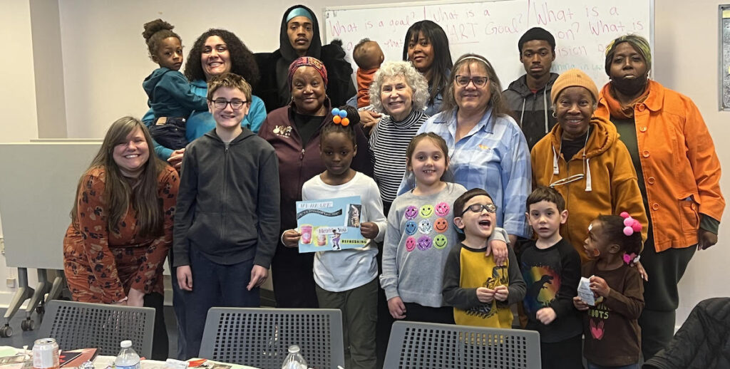 A diverse group of teens, grandparents and children stand before a wipe board. They are part of Connectedly's GrandFamily program.