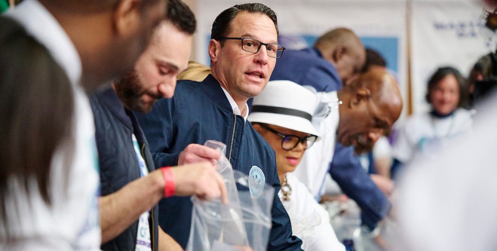 PA Governor Josh Shapiro (glasses, navy jacket), and advocate for increasing voter turnout, joined other elected officials and volunteers help assemble care packages for victims of gun violence still in the hospital on the 2024 King Day of Service at Girard College in Philadelphia. Photo by Albert Yee.