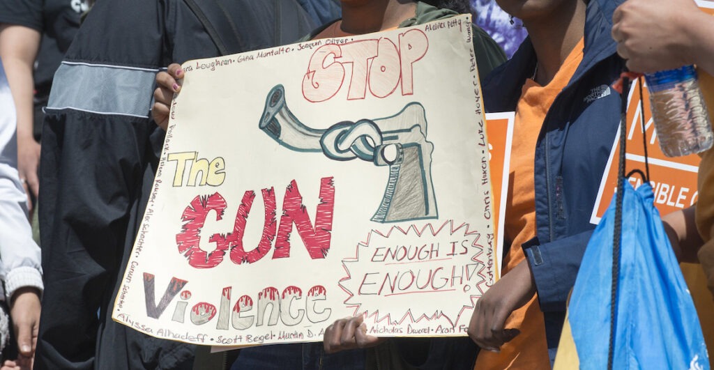 Teenagers hold a sign that says "Stop the Gun Violence. Enough is Enough!" at the National School Walkout for Gun Violence in 2018.
