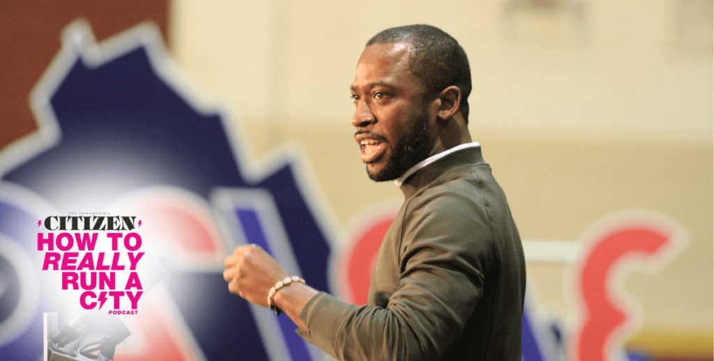 Richmond, Virginia Mayor Levar Stoney stands in profile, speaking. He is a Black man with a short beard, wearing an olive color shirt and bracelet and appears to be speaking to a crowd (not visible) with his left hand partially raised in a loose fist.