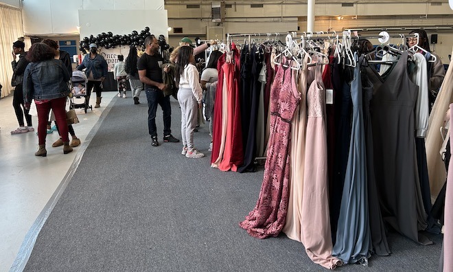 At Hoop Dreams' prom dress giveaway, A Cinderella Story. gowns hang from racks in an events space while people browse around.
