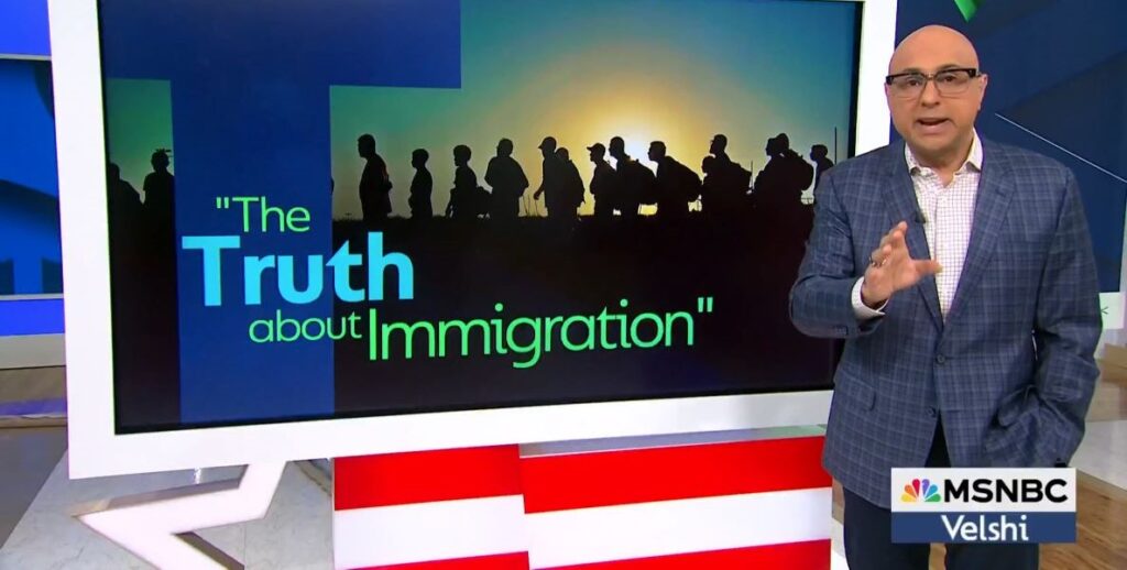 A large screen displays the words "the Truth About Immigration," beside which is a man with a bald head and black frame glasses, it is MSNBC host Ali Velshi