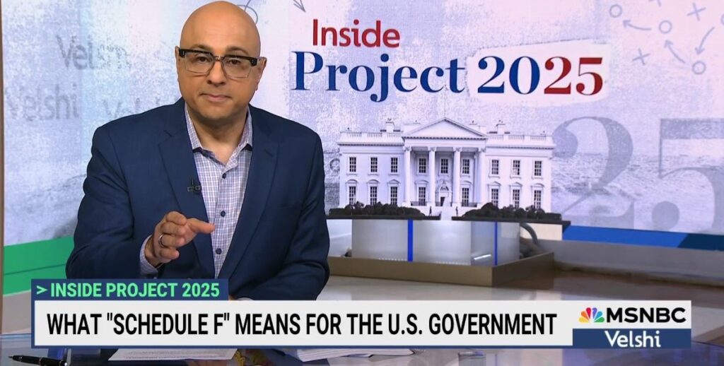 Ali Velshi, a bald man with glasses and a suit, sits at his desk in front of a Project 2025 graphic for his TV show. He's talking about Schedule F