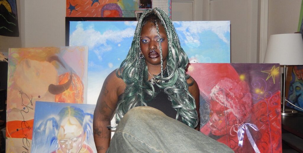 Artist Zeinab Diomande, a Black person with long, curled and braided green-ish grey hair, sit in front of five of their self portrait paintings.