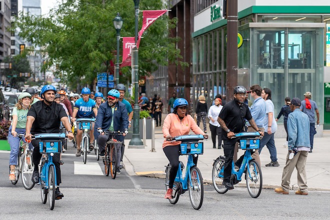 Philadelphia Mayor Cherelle Parker, an African American woman wearing a bike helmet, peach-color top and black leggings, rides a blue Indego bike with members of the Philadelphia Bicycle Coalition in Center City Philadelphia.