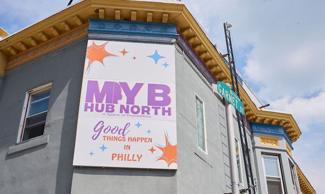 On the top floor of a corner building hangs a sign that says "MYB HUB NORTH" and "Good THINGS HAPPEN IN PHILLY." This is the exterior of Mom Your Business's HUB in the Allegheny West neighborhood of North Philadelphia.