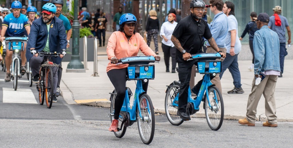 Philadelphia Mayor Cherelle Parker, an African American woman wearing a bike helmet, peach-color top and black leggings, rides a blue Indego bike with members of the Philadelphia Bicycle Coalition in Center City Philadelphia.