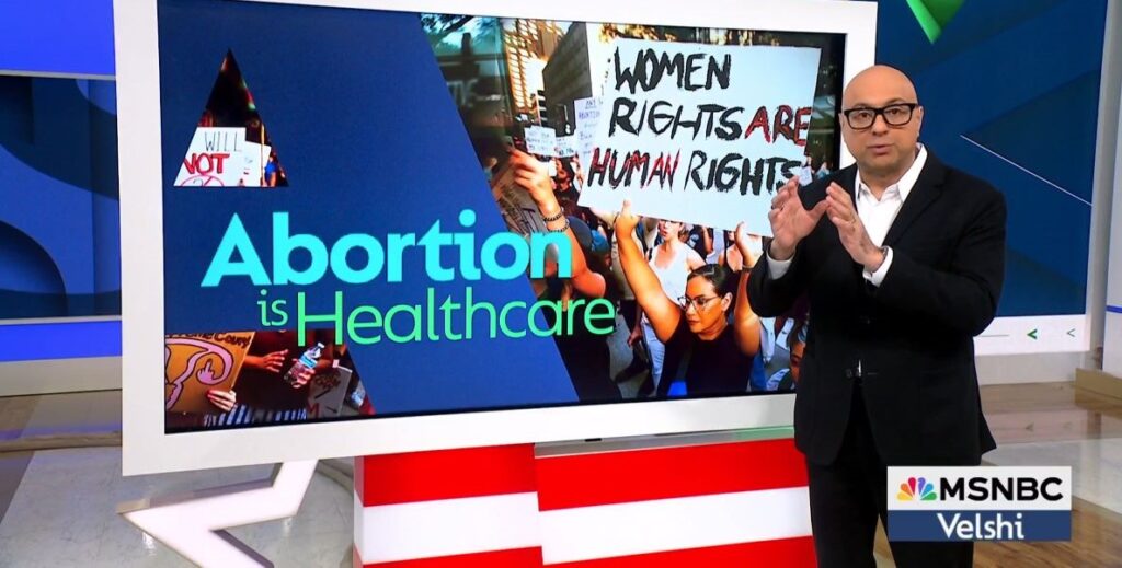 Ali Velshi, a bald man in a dark suit with glasses, stands to the right of a monitor with the graphic stating abortion is healthcare